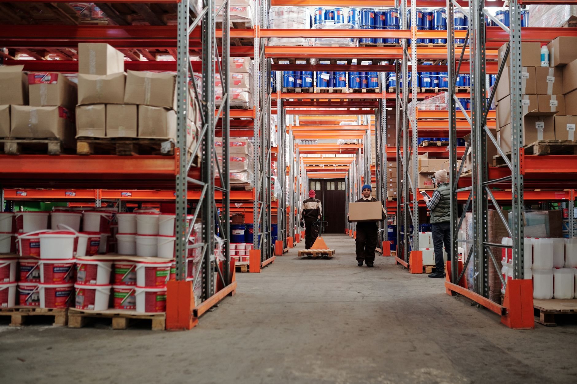Warehouse interior showing workers handling boxes and organized shelves filled with products
